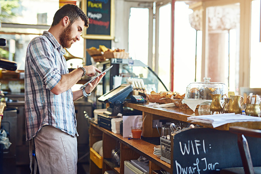 Shot of a young man using a digital tablet while working in a coffee shop